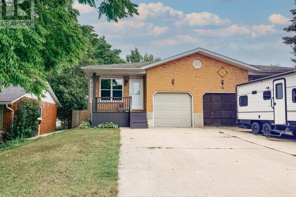 Aerial view of a suburban house with a double driveway, garage, and mature trees surrounding the property. - 54 Coleman Street, Huron East