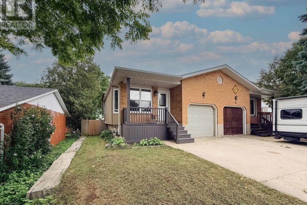 Living room with a large sectional sofa, recliner, ottoman, and hardwood floors. Open to dining area and stairs. - 54 Coleman Street, Huron East