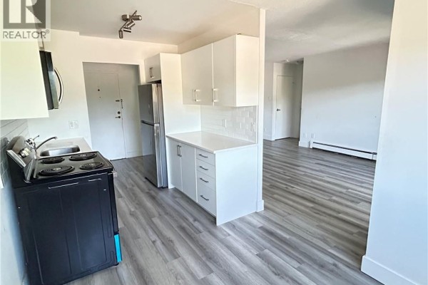 Kitchen area with white cabinets, stainless steel appliances, subway tile backsplash, and grey wood-look flooring. - 54 Country Hill Drive Unit# 318, Kitchener