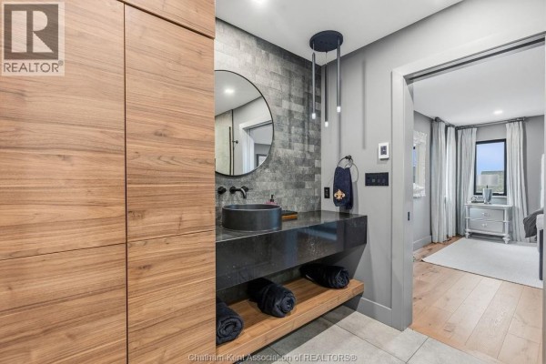 Modern bathroom with vessel sink and tile accent wall, opening to bedroom - 54 Dundee Drive West Chatham