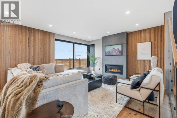 Modern living room with gas fireplace and wood accent wall - 54 Dundee Drive West Chatham