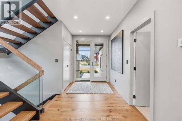 Modern kitchen with dark grey cabinets, wood accents, white marble countertops, and stainless steel appliances. - 54 Dundee Drive West, Chatham