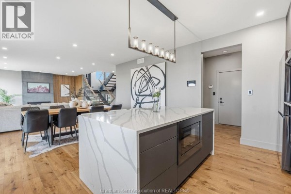 Modern kitchen island with quartz countertop, dining area, and living room - 54 Dundee Drive West Chatham