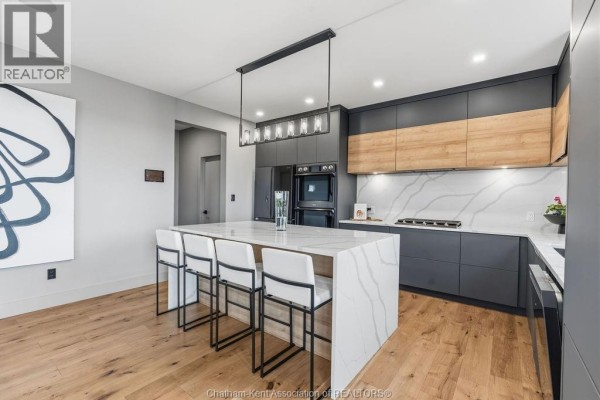 Modern kitchen with waterfall island, bar stools, and pendant lighting - 54 Dundee Drive West Chatham