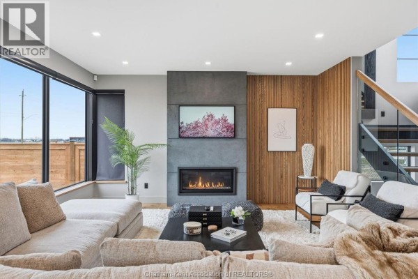 Living room with fireplace, TV, large window & wood accent wall - 54 Dundee Drive West Chatham