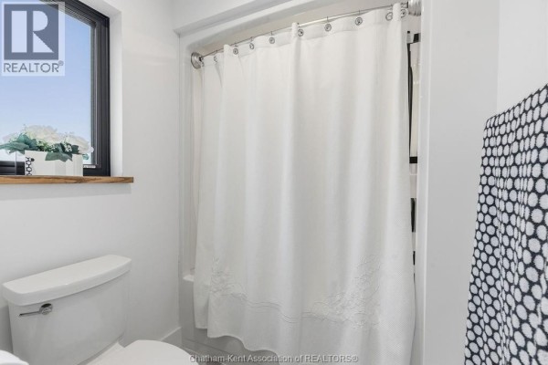 White toilet and shower curtain in bathroom with window - 54 Dundee Drive West Chatham