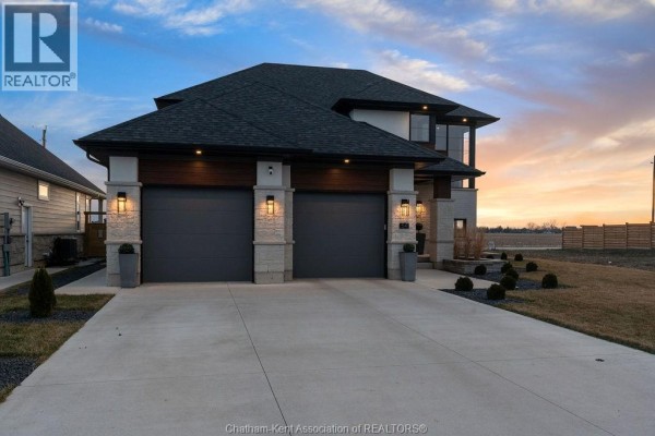 Modern home with double garage, stone pillars, and sunset sky - 54 Dundee Drive West Chatham