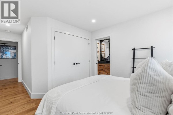 Modern bedroom with en-suite bathroom, wooden vanity, oval mirror, and decorative ladder - 54 Dundee Drive West Chatham