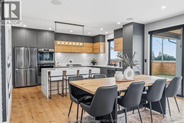 Modern kitchen with island and dining table, stainless steel appliances - 54 Dundee Drive West Chatham