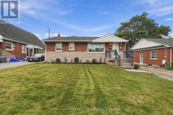 Front view of a brick bungalow with a large green lawn. - 54 Eastlawn Street, Oshawa