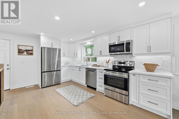 Modern white kitchen with stainless steel appliances and light wood floors. - 54 Eastlawn Street, Oshawa