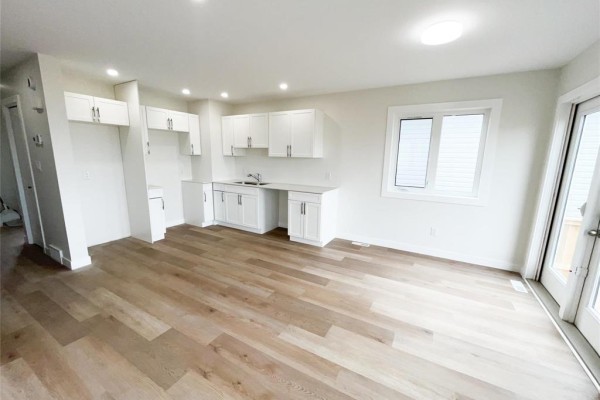 Open concept living area with white cabinetry, stainless steel sink, light wood flooring, and a window. - 54 Feathertail Way, New Bothwell