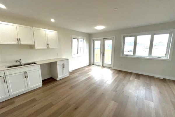 Living area with a kitchen counter, white cabinets, and multiple windows offering natural light. - 54 Feathertail Way, New Bothwell