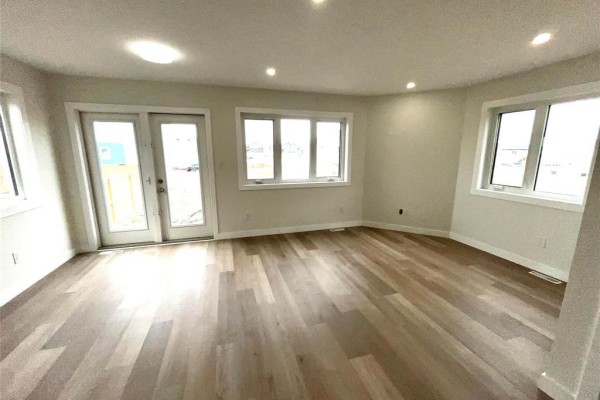 Spacious living area with light wood flooring, large windows, and French doors leading outside. - 54 Feathertail Way, New Bothwell
