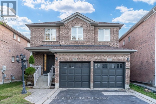 Front facade of a two-story brick house with a double garage and arched windows. - 54 Ferncroft Place, Brampton