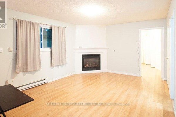 Rear yard with green grass, mature trees, and a wooden fence bordering the property. - 54 Gunn (unit B) Street, London North