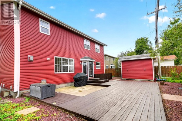 Backyard of red house with a large wooden deck and a detached garage. - 54 Halley Drive, St  John S