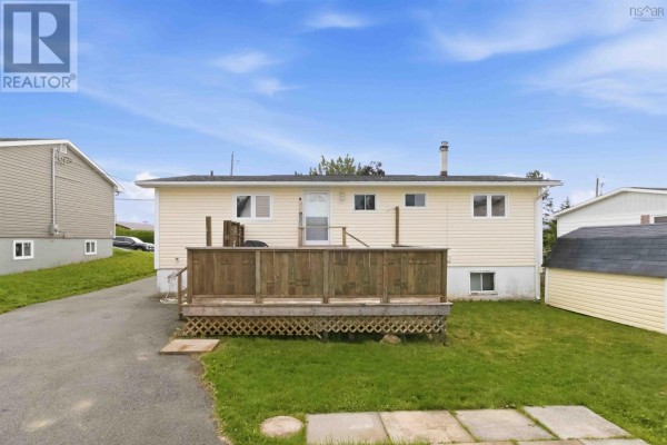 Rear exterior of a beige siding house with a wooden deck and a green lawn, driveway on left. - 54 Himmelman Drive, Eastern Passage