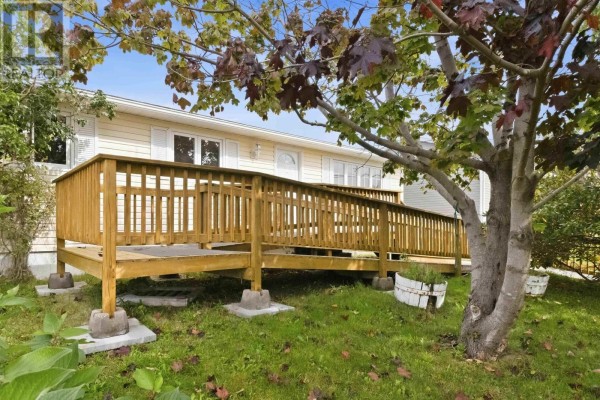 A long wooden wheelchair ramp leads to the beige siding house with a driveway and a garage in the background. - 54 Himmelman Drive, Eastern Passage