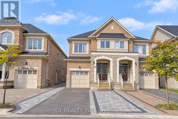 Exterior view of a modern townhouse complex with brick and stone facades and driveways. - 54 Mohandas Drive, Markham