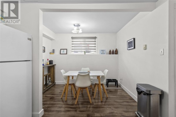 A dining area with a white table and four white chairs. A window with horizontal blinds is visible on the back wall. - 54 Nash Crescent, Mount Pearl