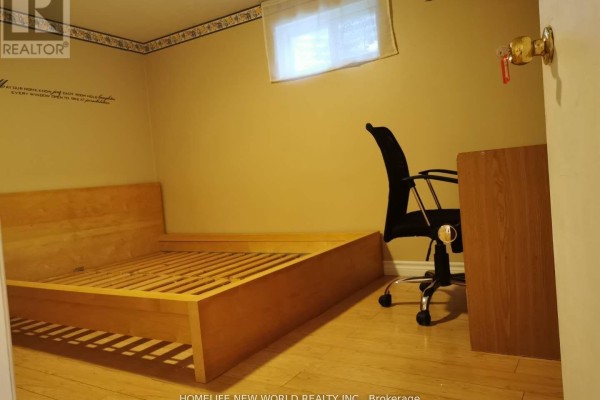 Basement bedroom with a wooden bed frame, desk, office chair, and a window. - 54 Painswick Crescent, Toronto