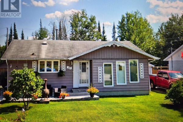 Front exterior of a single-story, light purple wood-sided house with a grey roof and green lawn. - 54 Redwing Ave, Manitouwadge