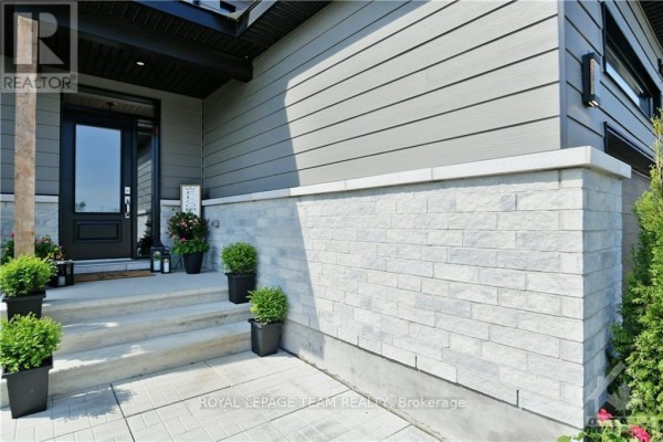 Entrance to the house showing concrete steps, grey siding, and light stone. - 54 Reynard Crescent, Ottawa