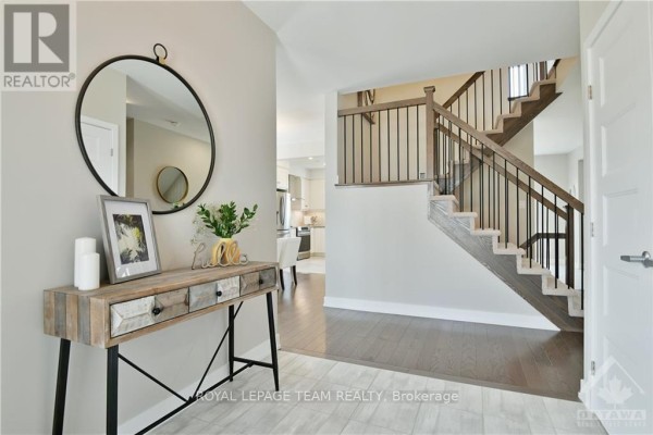 Entryway with a staircase, wood console table with a mirror, and wood flooring. - 54 Reynard Crescent, Ottawa