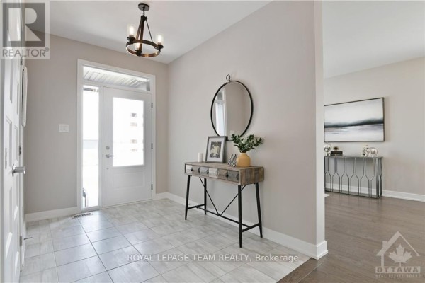 Foyer with tiled floor, white door, console table, mirror, and view of living room. - 54 Reynard Crescent, Ottawa