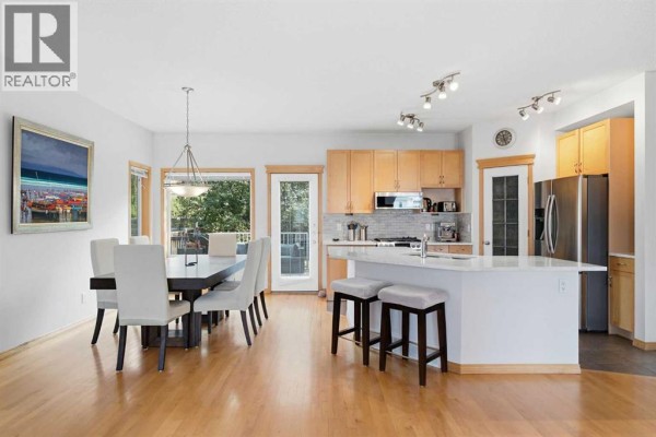 Open concept dining area and kitchen with light wood cabinets and a large island. - 54 Rockyledge Rise Nw, Calgary