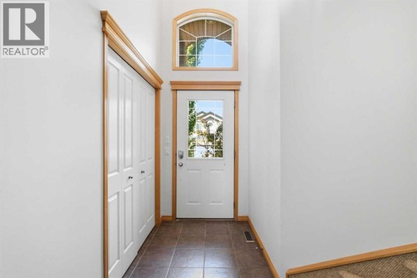 Entryway with a white door, arched window, and dark tile flooring. - 54 Rockyledge Rise Nw, Calgary