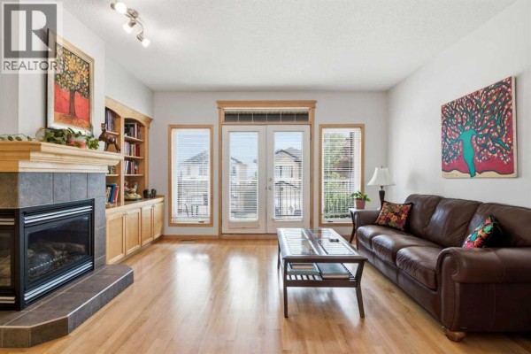 Living room with a gas fireplace, built-in bookshelves, and a leather sofa. - 54 Rockyledge Rise Nw, Calgary