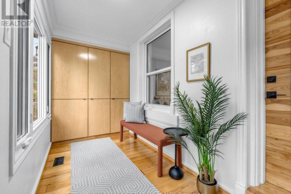 Foyer with light wood built-in cabinets, a rust bench, a plant, and a patterned rug. - 54 Roseheath Avenue, Toronto