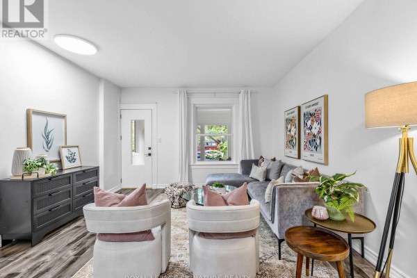 Living room with a grey sectional sofa, two cream chairs, a grey dresser, and a floor lamp. - 54 Roseheath Avenue, Toronto