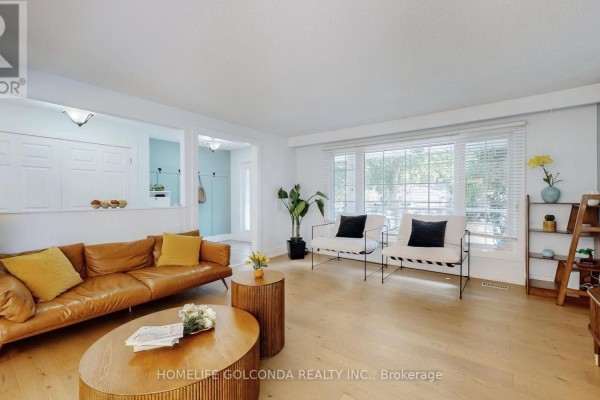 Living room featuring a brown leather sofa and large windows - 54 Senator Reesor's Drive, Markham