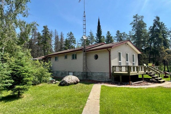Side view of a beige house with a deck, surrounded by green trees and grass. - 54 Steck Drive, Belair