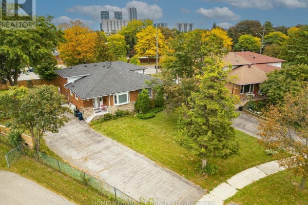 Aerial view of a bungalow with a driveway, lawn, and surrounding trees. - 54 Sunderland Crescent, Toronto