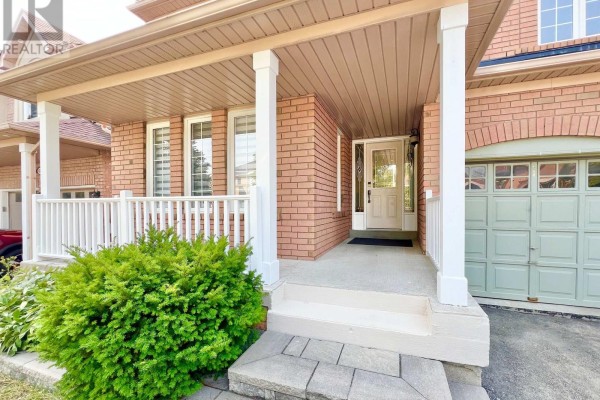Close-up of the covered front porch with white railing, brick pillars, and the front door with glass sidelights. - 54 Treasure Road, Vaughan