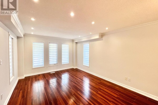 Spacious living room with dark wood floors, beige walls, and three large windows with roller blinds. - 54 Treasure Road, Vaughan