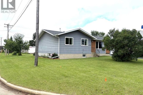 Side view of a gray house with white trim and windows, set on a green lawn. - 5402 47 Avenue W, Forestburg