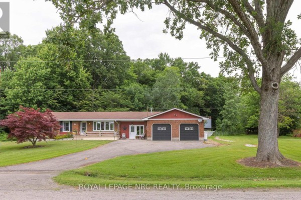 Front exterior of a red brick bungalow with a covered porch and two-car garage. - 54038 Willford Road, Wainfleet