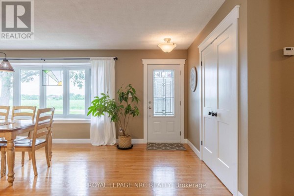 Interior entryway with a glass-paned front door, hardwood floors, and a large bay window. - 54038 Willford Road, Wainfleet