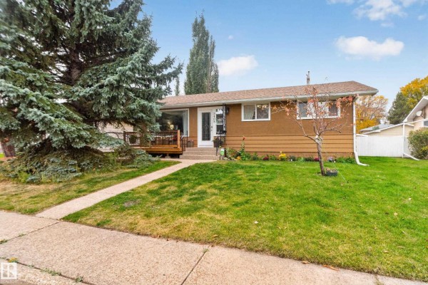 Entryway with a patterned rug, bench, and a glass-paned front door. - 5408 47a St, Wetaskiwin