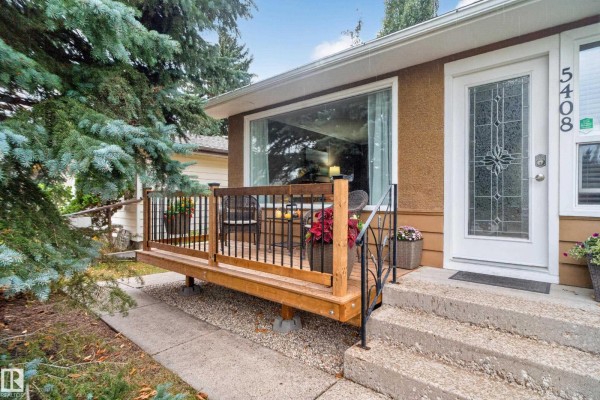 Living room with a large window, wood laminate flooring, and a decorative fireplace. - 5408 47a St, Wetaskiwin