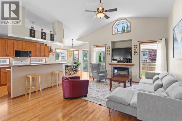 Living room and kitchen area with wood cabinets, island, dining table, and seating. - 5408 59 Street, Camrose