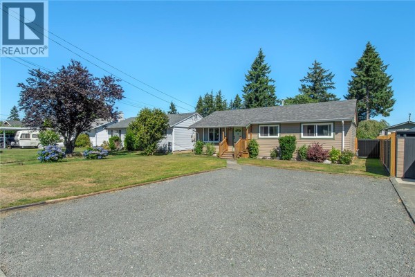 View of the house exterior from the driveway, showing the front entrance and lawn. - 541 Colwyn St, Campbell River
