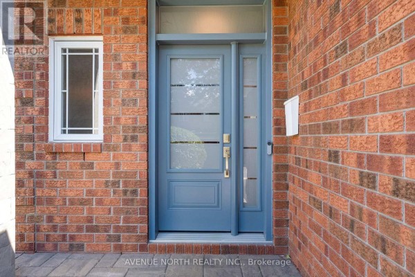 Close-up of the blue front door and adjacent brick wall with a window. - 541 Wild Shore Crescent, Ottawa