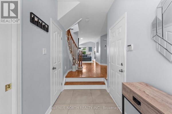 Interior entryway showing a staircase with hardwood treads, light blue walls, and two doors. - 541 Wild Shore Crescent, Ottawa