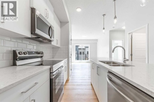 Kitchen with white cabinets, stainless steel oven, subway tile backsplash, and island. - 5413, 20295 Seton Way Se, Calgary